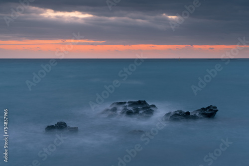 A rocky shoreline with a calm ocean in the background