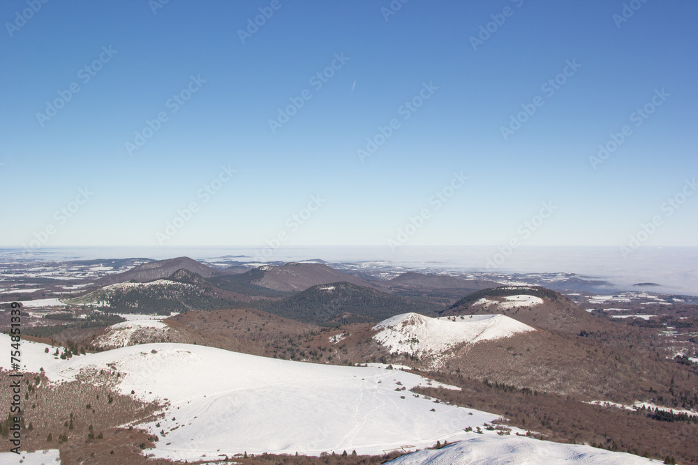 Landscape in Auvergne. View of the Chaine des Puys. Winter landscape. Snow and volcanoes. Blue sky. Nature