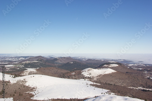 Landscape in Auvergne. View of the Chaine des Puys. Winter landscape. Snow and volcanoes. Blue sky. Nature