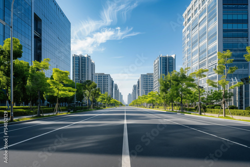 Wide empty city street flanked by green trees and modern skyscrapers