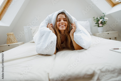a woman is laying on a bed under a blanket and smiling
