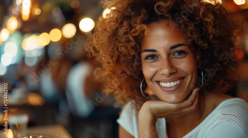 A multiracial woman with curly hair smiling directly at the camera