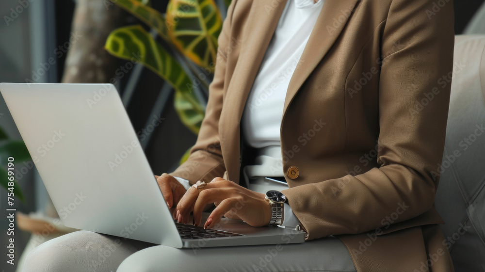 Obraz premium Businesswoman typing intently on a laptop in a modern office setting.