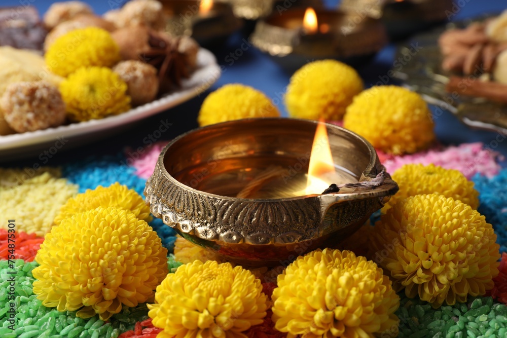 Diwali celebration. Diya lamps, colorful rangoli and chrysanthemum flowers on table, closeup