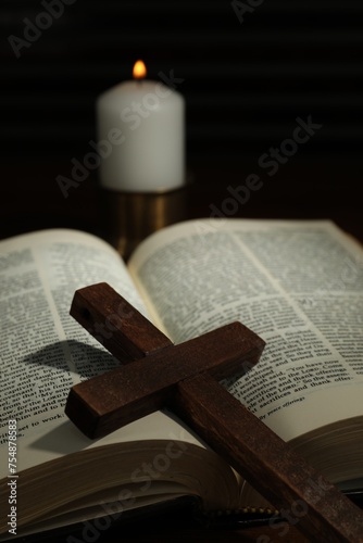 Wooden cross, Bible and church candle on table