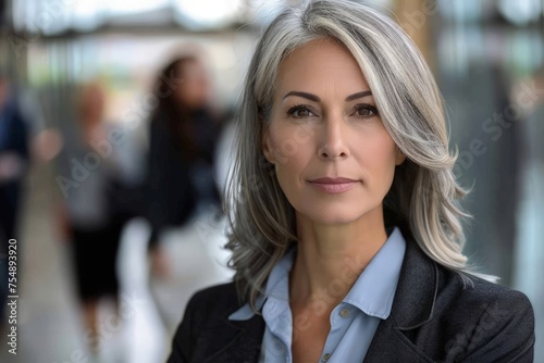 A middle aged business woman with grey hair wearing a blue shirt. © pham