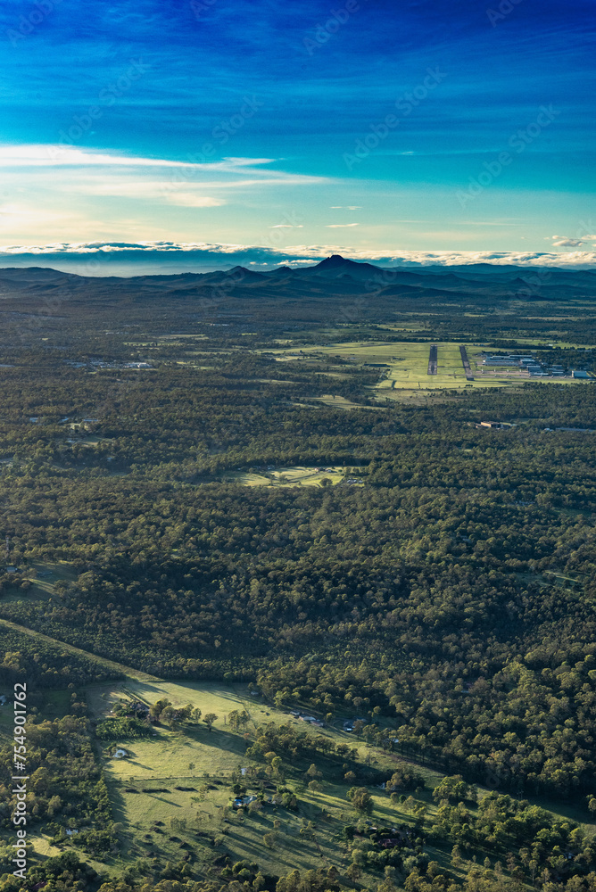 Vue aérienne verticale d'un paysage de la campagne située à l'Ouest de la ville d'Ipswich (Queensland, Australie), avec des forêts, un aéroport et une chaine de montagnes.