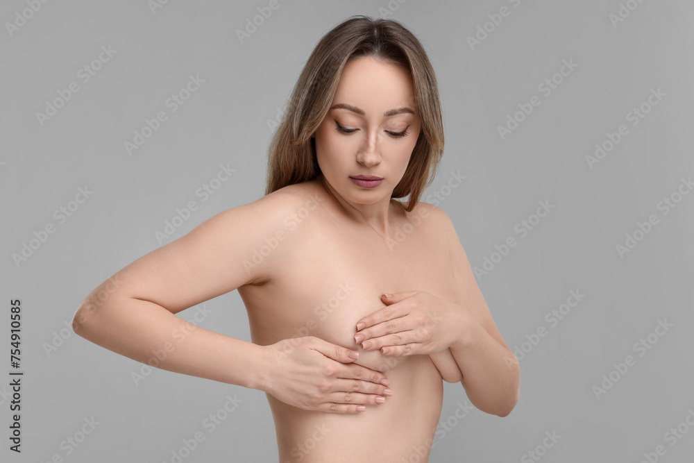 Mammology. Naked young woman doing breast self-examination on light grey background Mammology. Naked young woman doing breast self-examination on light grey background