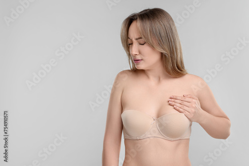 Mammology. Young woman doing breast self-examination on light grey background, space for text