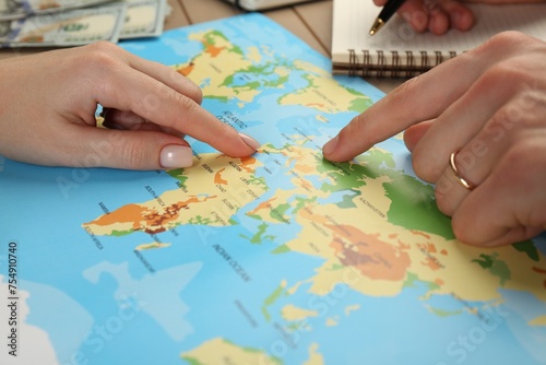 Man and woman planning their honeymoon trip with world map at table, closeup
