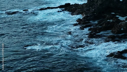 Sea volcanic rocks breaking waves in evening time
