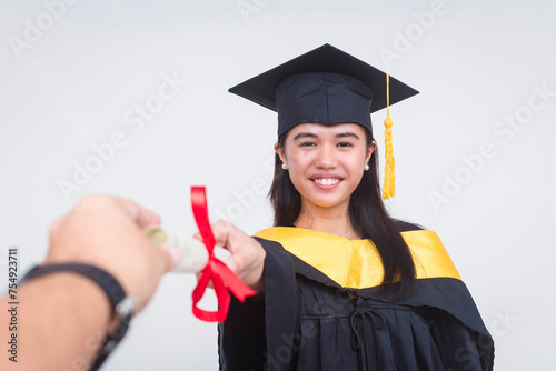 An upbeat female graduate of bachelor of science is handed her diploma while looking at the camera. Full body photo isolated on a white background. photo
