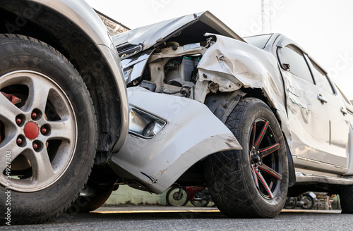 Close-up, low angle view of the front side wheels of a white car which was badly damaged.