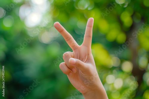 Close-up of a hand making a peace sign with two fingers raised at outdoor