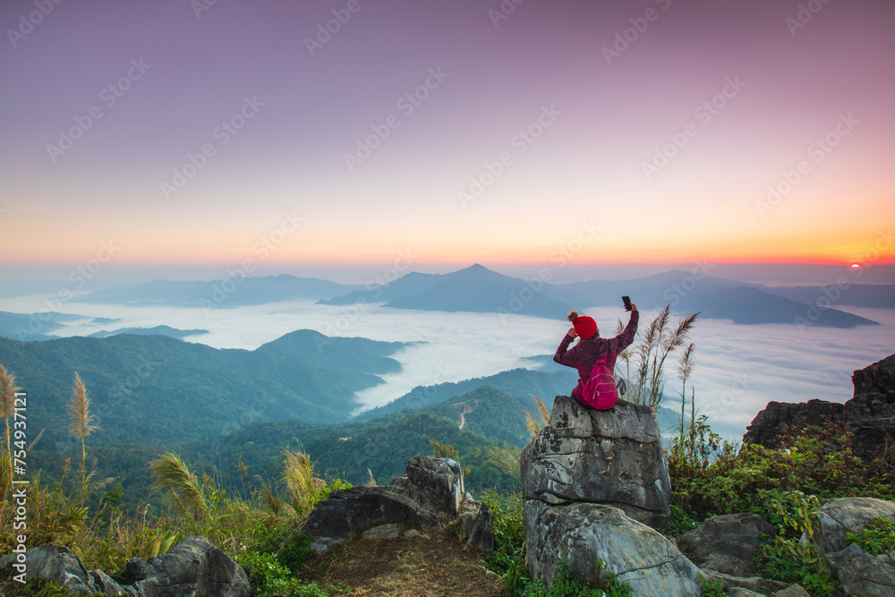 Young woman  in red jacket hiking on the high mountain, Doi Pha Tang, Chiang Rai province, border  of  Thailand and Laos.