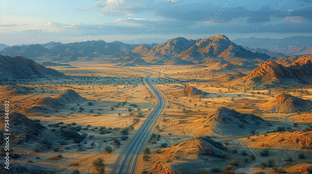 Curved road winding through a desert landscape with mountains under a sunset sky.