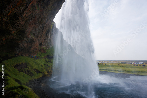 Seljalandsfoss  a famous and unique waterfall in Iceland with visitors walking behind the falls into a small cave. Trip concept.