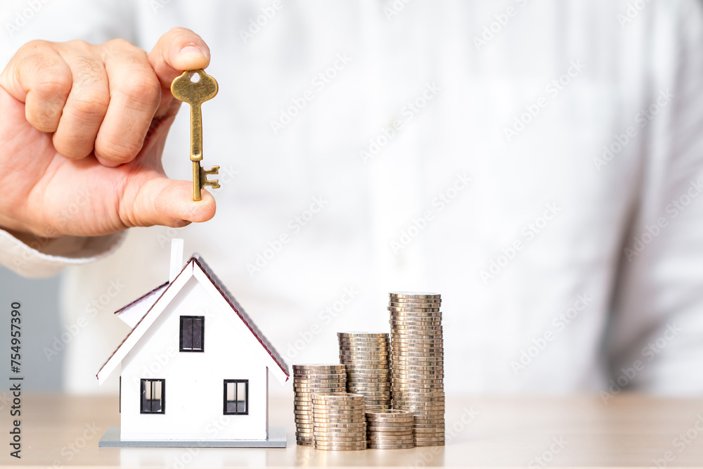 Businessman hand holding the house key and the home model and stack ...