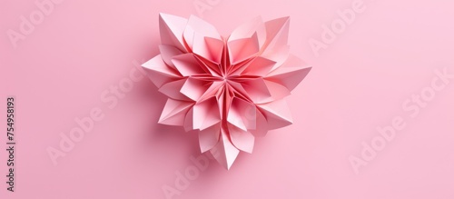 A magenta paper flower with peach petals is displayed on a pink background, showcasing artistic creativity and symmetry in a triangular pattern