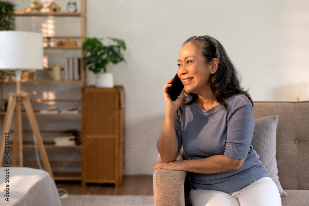 Relaxed senior asian woman having a pleasant phone conversation seated comfortably in her cozy living room. Relaxed senior asian woman having a pleasant phone conversation seated comfortably in her cozy living room.