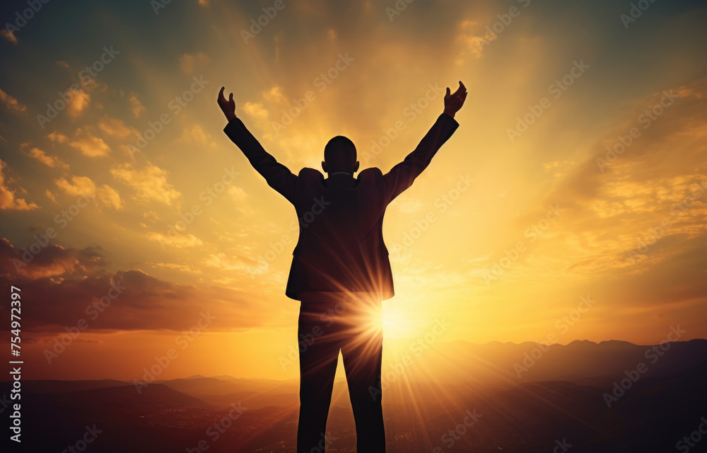 A man is standing in the mountains with his arms raised in the air