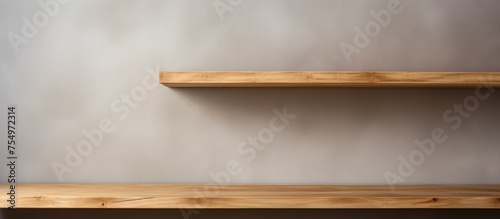 A couple of empty wooden shelves are seen resting on top of a wall with a gray background. These shelves are suitable for product display and decoration.