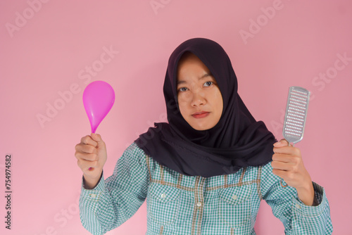 Portrait of happy asian woman wearing kitchen apron isolated on grey background while carrying cooking ware