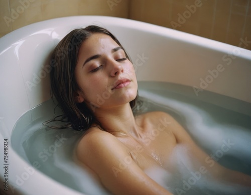 Woman in a bath with her eyes closed, enjoying the shower. Concept of Hygiene, frequency, romance, relaxation, rest.