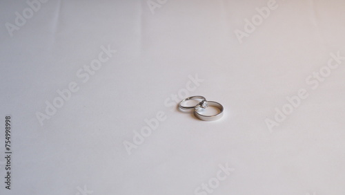 a diamond ring (engagement ring) and a silvery plain band (wedding band), white background