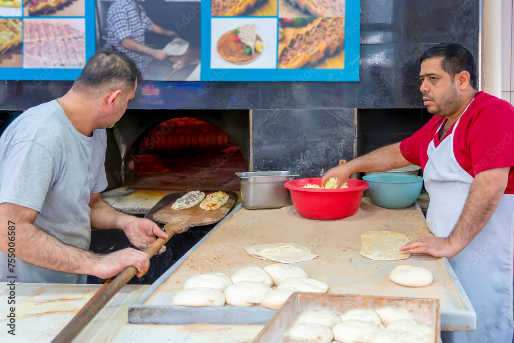 Pizza ready to bake in the woodfired oven. Chef is putting freshly made