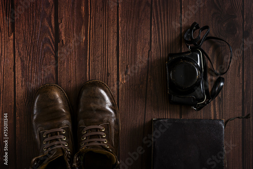 a composition with leather boots, an old book and a camera obscura case on  a dark wooden surface photo