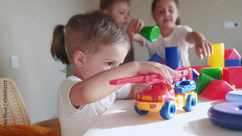kids girl and baby boy play in kindergarten. a group of children play indoor toys cubes and cars on the table in kindergarten. happy family preschool education concept. nursery baby toddler home kids girl and baby boy play in kindergarten. a group of children play indoor toys cubes and cars on the table in kindergarten. happy family preschool education concept. nursery baby toddler home