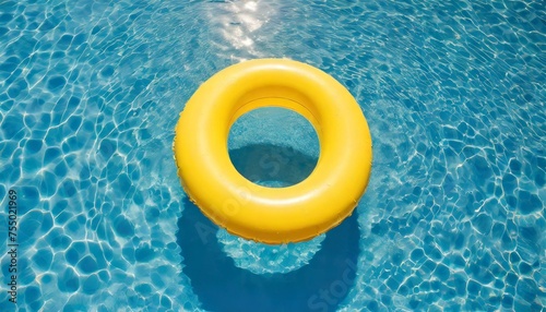 yellow swimming pool ring float in blue water. concept color summer. top view 