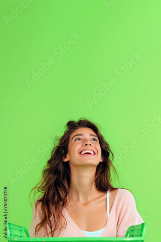 Woman holding a supermarket shopping basket on green background. Advertisement, promotions, sale, ecology, sustainability, green initiatives. Copy space for text. Creative supermarket shopping concept