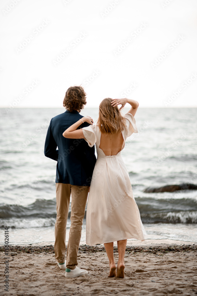 Beautiful and slim newlyweds admire the waving sea Beautiful and slim newlyweds admire the waving sea