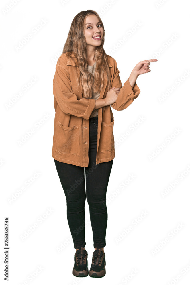 Studio portrait of a blonde Caucasian woman smiling cheerfully pointing with forefinger away.