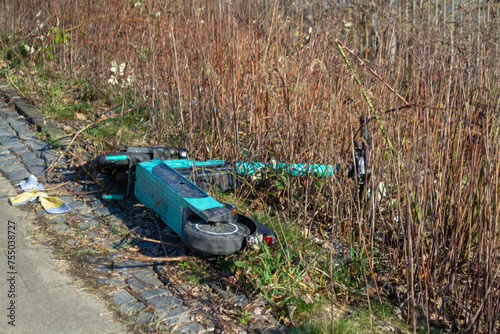 Electric scooter abandoned. Ein im Gras liegender Elektroroller. photo