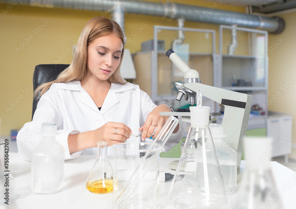 Woman laboratory assistant. Lady works as chemist. Laboratory assistant sits at table with microscope. Girl student biological university. Lab glassware near biologist. Woman studying biotechnology Woman laboratory assistant. Lady works as chemist. Laboratory assistant sits at table with microscope. Girl student biological university. Lab glassware near biologist. Woman studying biotechnology