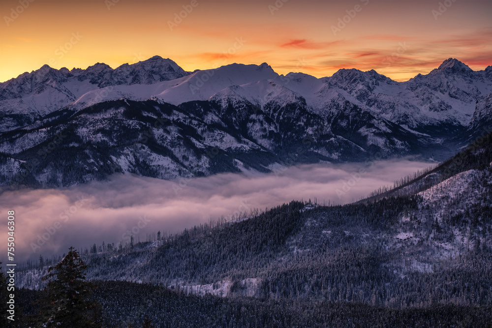 Panoramic view from Gesia Szyja peak in Tatra mountains. Colorful morning sky over snowy peaks of High Tatras in the winter season.