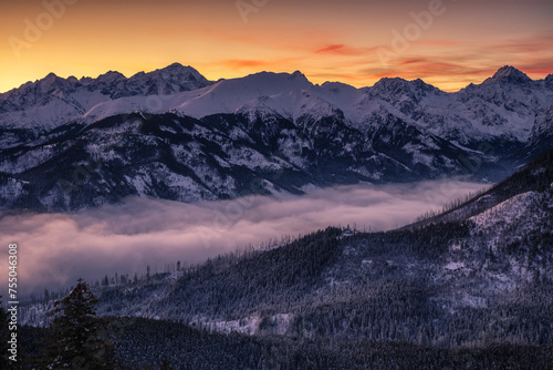Panoramic view from Gesia Szyja peak in Tatra mountains. Colorful morning sky over snowy peaks of High Tatras in the winter season.