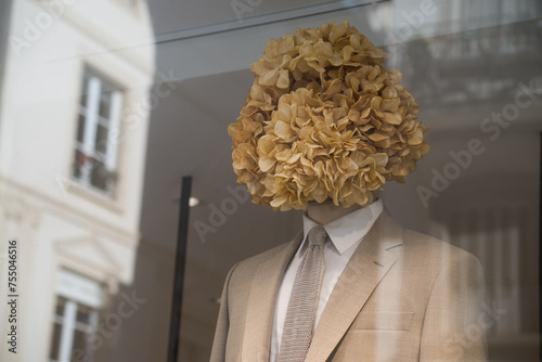 Closeup of brown wedding suit on mannequin with a hortensia head in wedding store showroom