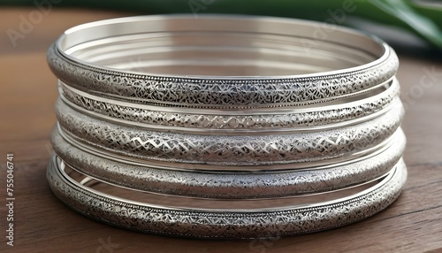 A Stack Of Slim Silver Bangles Engraved With Intri