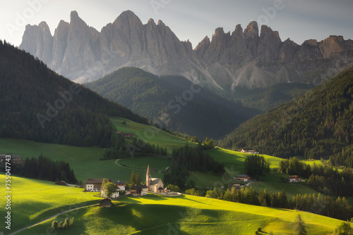 Santa Maddalena village in front of the Geisler or Odle Dolomites Group, Val di Funes, Trentino Alto Adige, Italy, Europe. Blue sky and green grass in Summer, August