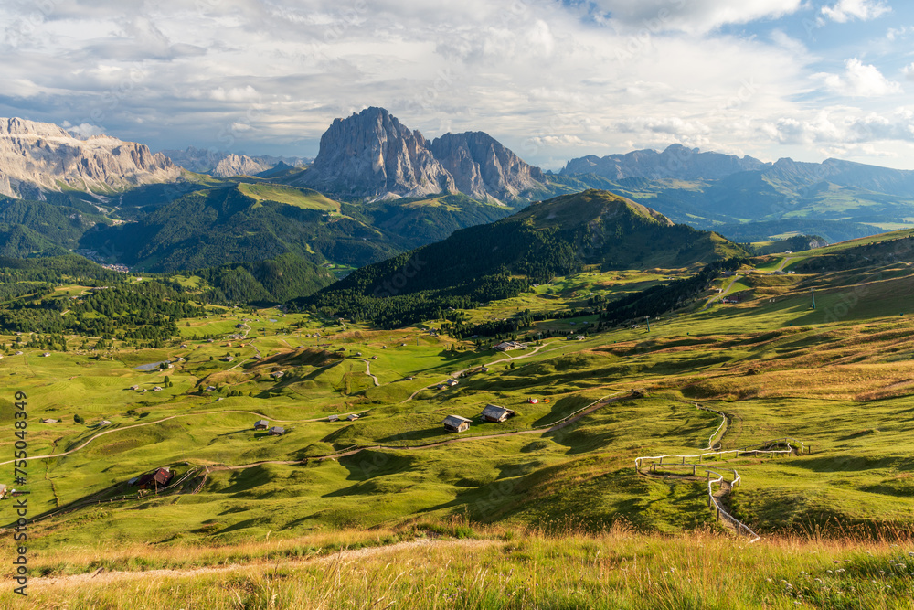 View from Seceda mountain on the Val Gardena in the Italian Dolomites in sunny sumer day with green grass in foreground and blue sky with clouds.