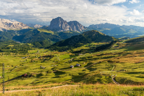 View from Seceda mountain on the Val Gardena in the Italian Dolomites in sunny sumer day with green grass in foreground and blue sky with clouds.
