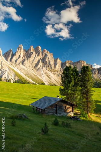 Wooden hut in Dolomites mountain Italy. Popular tourist attraction near Geisleralm Rifugio Odle at warm august day with Odle group mountain in the background and blue cloudless sky photo