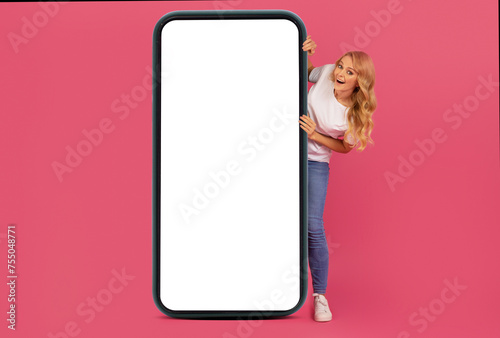 Smiling blonde lady presents large touchscreen of mobile phone, mockup