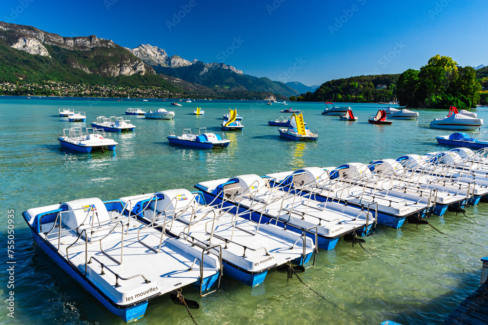 Paddle boats on Annecy Lake with swans island and mountains in background