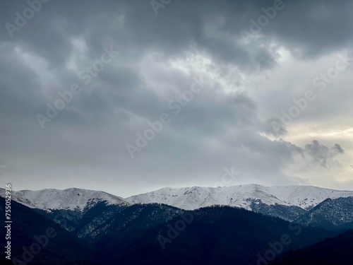 Snow-covered mountains under a cloudy sky © Wirestock
