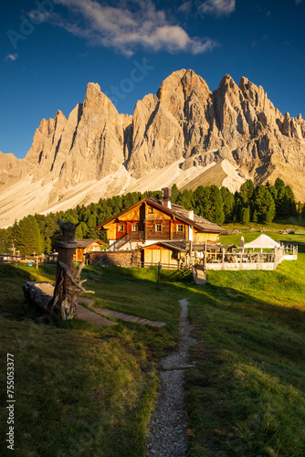 Vertical path to Rifugio Odle in Dolomites mountain Italy in warm summer day in august with Odle group mountain in the background at warm light and blue sky with little cloud photo